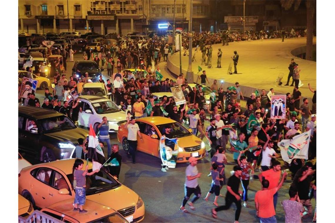 Schiitischer Geistlicher Al-Sadr wohl Wahlsieger im Irak Anhänger des schiitischen Klerikers Al-Sadr feiern mit seinen Plakaten nach der Bekanntgabe der Ergebnisse der Parlamentswahlen auf dem Tahrir-Platz in Bagdad. Foto: Hadi Mizban/AP/dpa