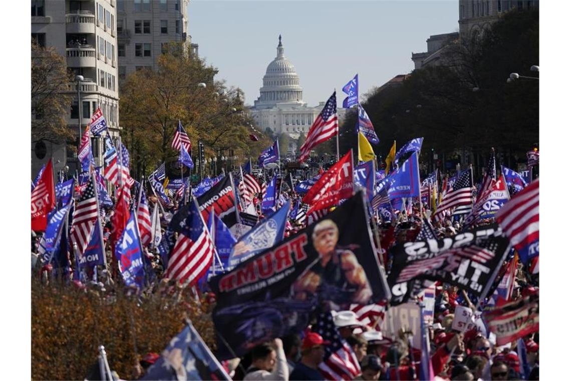 Anhänger von US-Präsident Trump halten amerikanische Fahnen und versammeln sich zu dessen Unterstützung bei einem Protest vor dem Hintergrund des Kapitols. Foto: Julio Cortez/AP/dpa