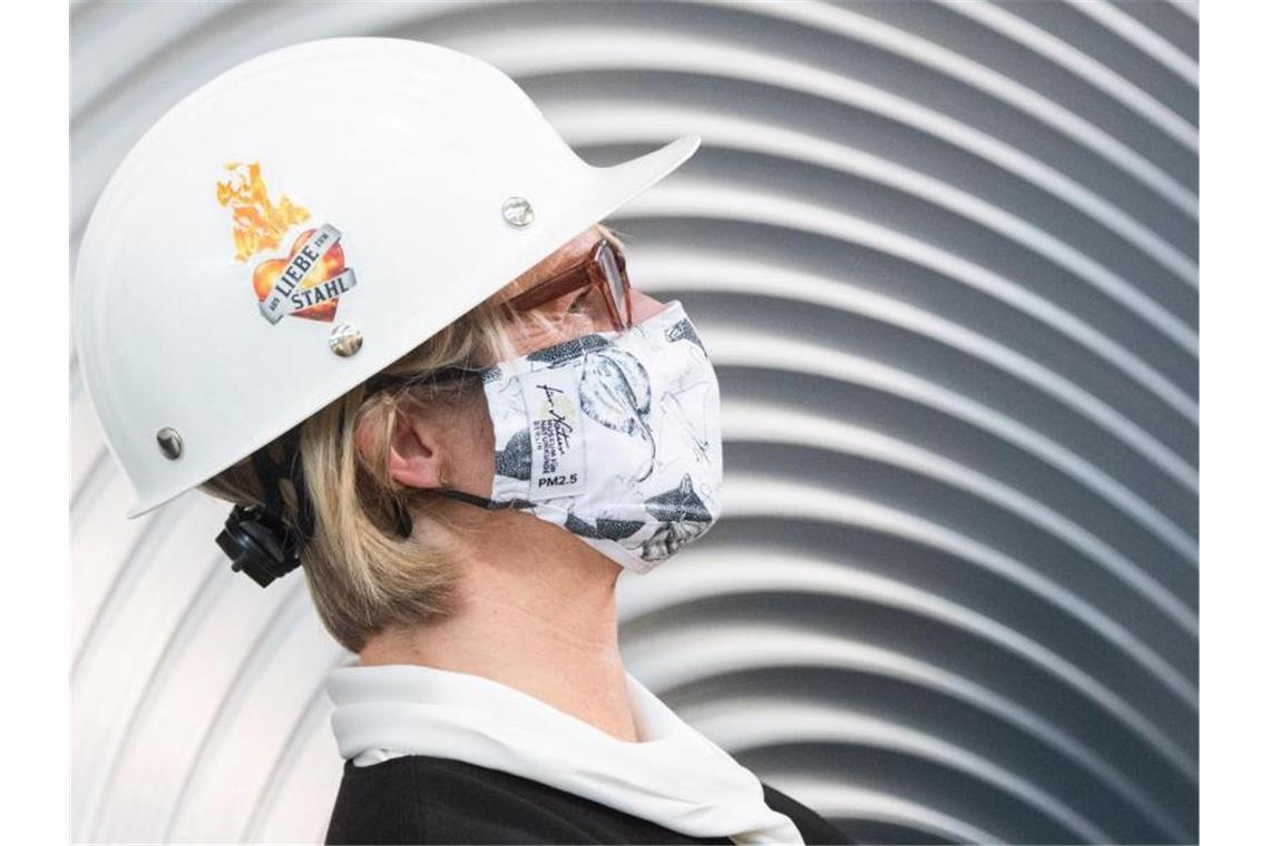 Anja Karliczek, Bundesministerin für Bildung und Forschung, trägt einen Mund-Nasenschutz und einen Helm im Werk der Salzgitter AG. Foto: Julian Stratenschulte/dpa