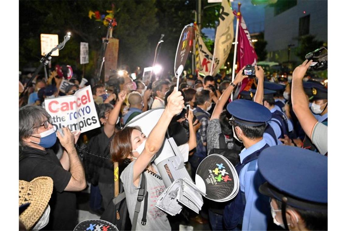 Olympioniken fahren heim - Japans Regierung in der Kritik Anti-Olympia-Demonstranten in der Nähe des Nationalstadions vor der Abschlussfeier. Foto: -/kyodo/dpa