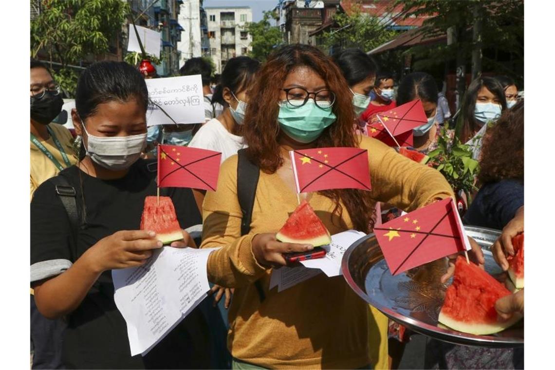 Anti-Putsch-Demonstranten tragen während eines Protests Wassermelonenstücke, in denen durchgestrichene chinesische Fähnchen stecken. Foto: --/AP/dpa