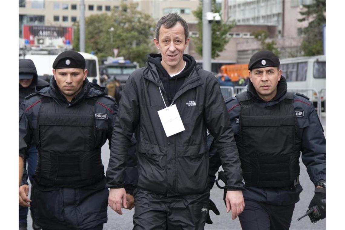Zehntausende Menschen demonstrieren in Moskau Anton Chernyak (M), Rapper und Mitglied der russischen Rapgruppe „Krovostok“, verlässt nach einem Auftritt flankiert von Polizisten den Protest. Foto: Alexander Zemlianichenko/AP