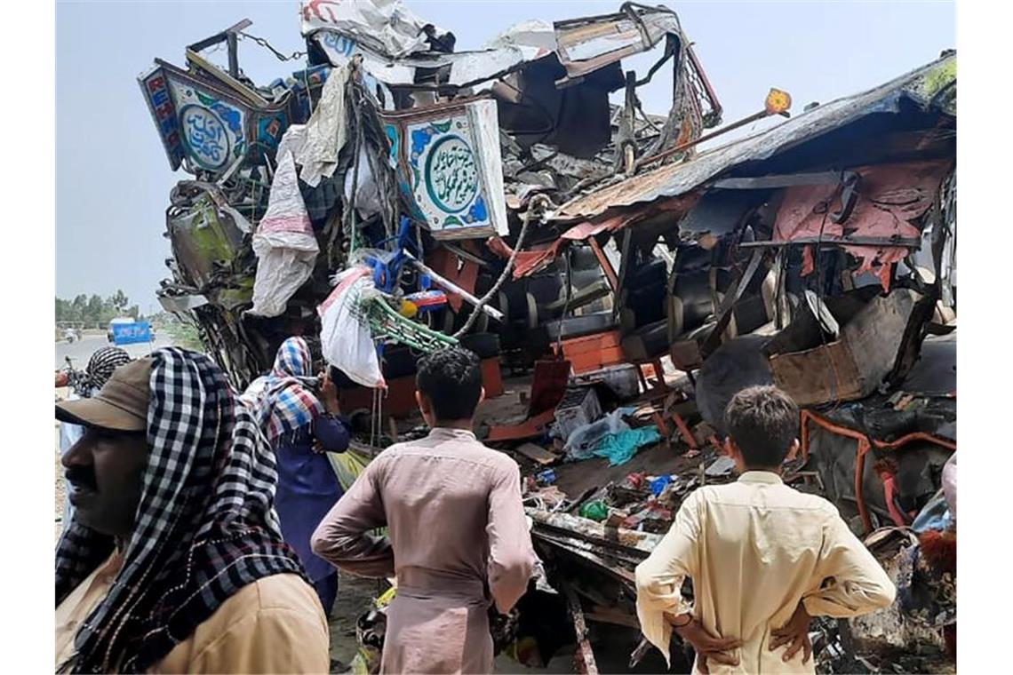 Mindestens 28 Tote bei Busunfall in Pakistan Anwohner betrachten das Wrack des Busses an der Unfallstelle in der Nähe von Dera Ghazi Khan. Foto: Saleem Khan/AP/dpa
