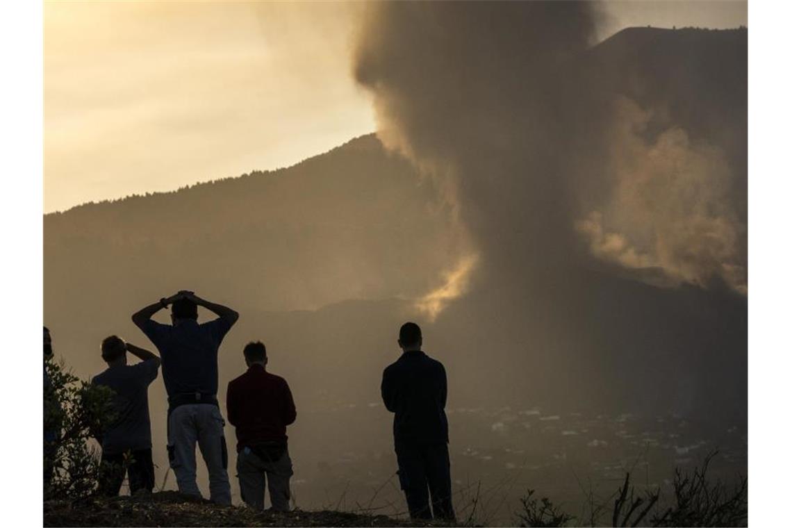 Anwohner blicken von einem Hügel aus auf die Lava, die weiterhin aus dem Vulkan auf der Insel La Palma fließt. Foto: Emilio Morenatti/AP/dpa