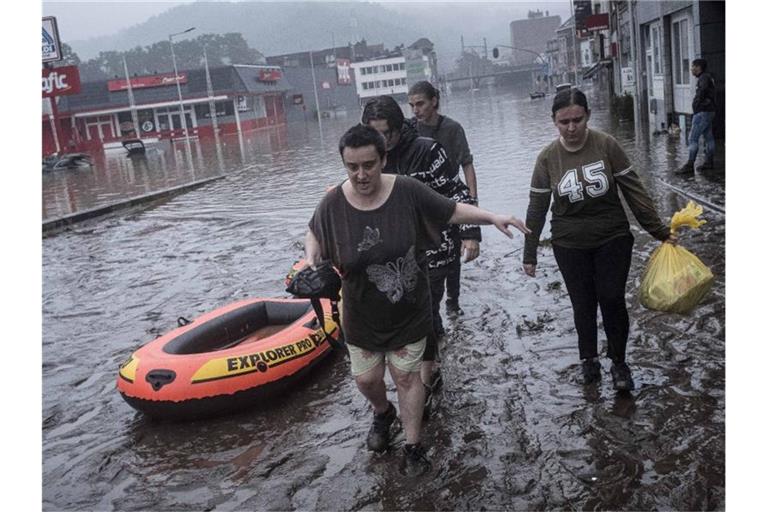 Anwohner in Lüttich waten mit einem Gummiboot durch das Wasser, nachdem die Maas bei schweren Überschwemmungen über die Ufer getreten ist. Foto: Valentin Bianchi/AP/dpa