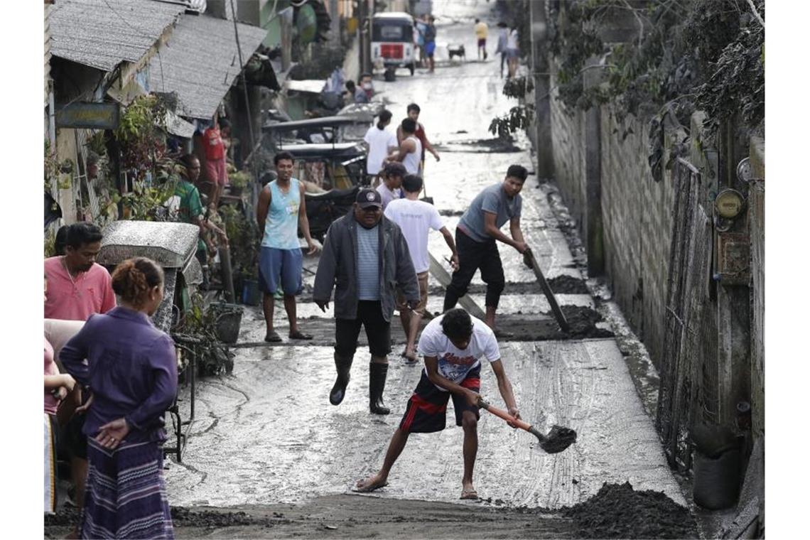 Anwohner reinigen eine Straße von Asche. Der Vulkan Taal ist nach dem Mayon der zweitaktivste Vulkan des südostasiatischen Inselstaats. Foto: Aaron Favila/AP/dpa