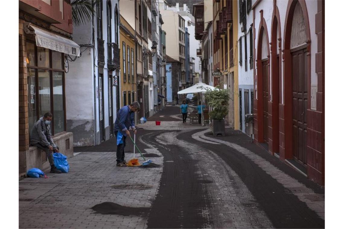 Anwohner säubern die Straße in Santa Cruz de la Palma von Asche. Foto: Saul Santos/AP/dpa