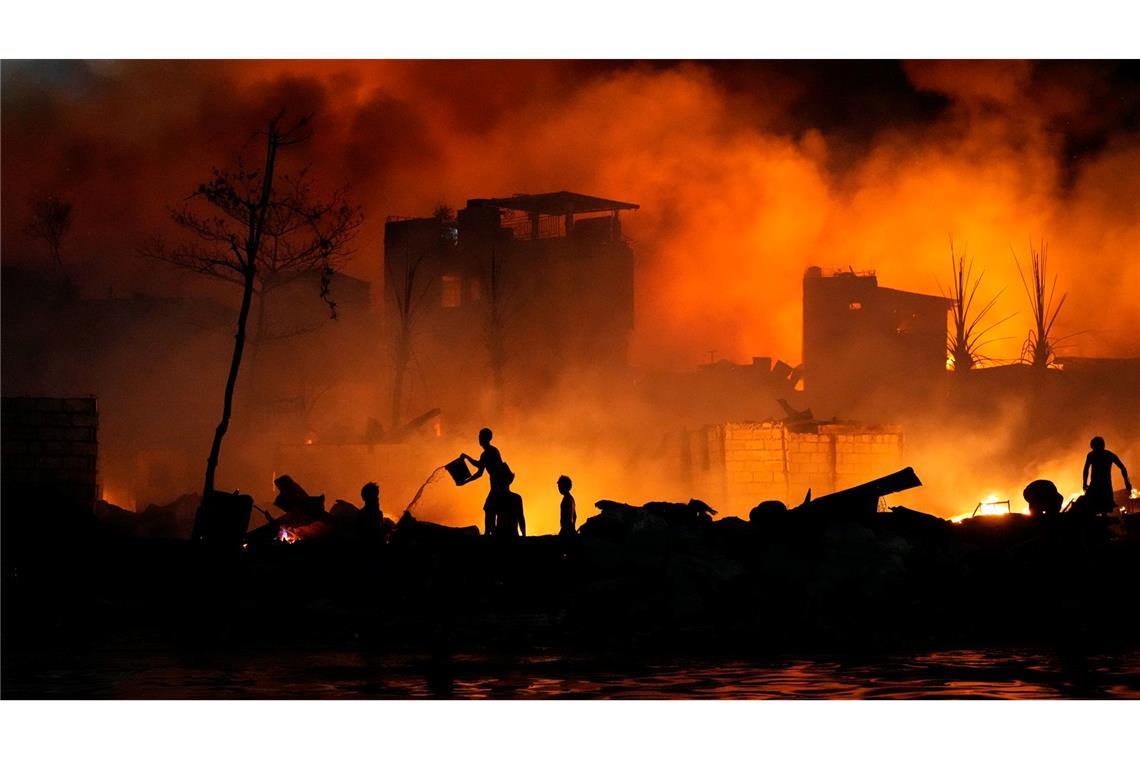 Anwohner versuchen mit Wassereimern ein Feuer zu bekämpfen, das in einer Armensiedlung in Manila ausgebrochen ist.
