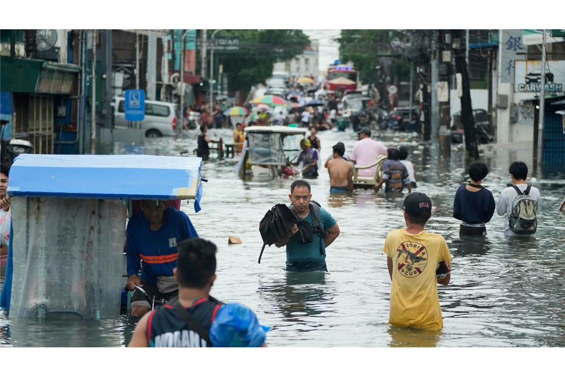 Bilder des Tages Anwohner waten durch eine überschwemmte Straße auf den Philippinen.