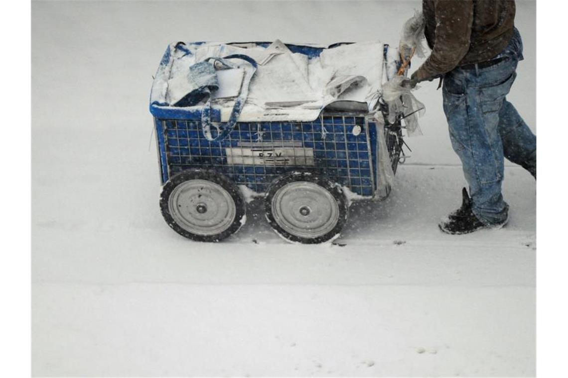 Arbeiten zum Mindestlohn: Ein Zeitungszusteller ist am frühen Morgen bei dichtem Schneetreiben in Berlin unterwegs. Foto: Daniel Reinhardt/dpa