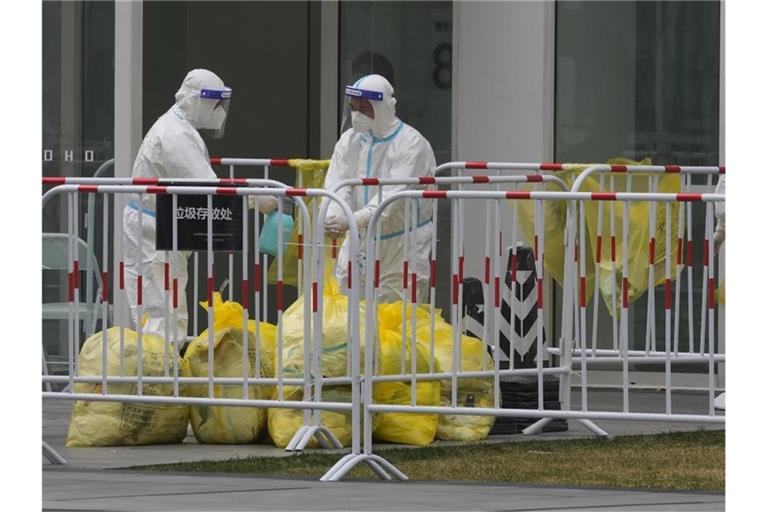 Arbeiter desinfizieren sich gegenseitig, nachdem sie in Kontakt mit Müllsäcken gekommen sind, die in Bürogebäuden mit Corona-Fällen gefunden wurden. Foto: Ng Han Guan/AP/dpa