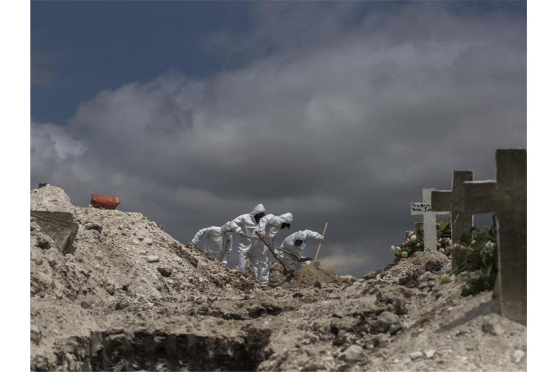 Arbeiter in Schutzanzüge heben im mexikanischen Tijuana ein Grab aus. Foto: Omar Martínez/dpa