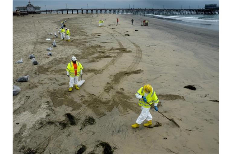 Arbeiter in Schutzanzügen reinigen den Strand nach einem Ölaustritt in Newport Beach, Kalifornien. Foto: Ringo H.W. Chiu/AP/dpa