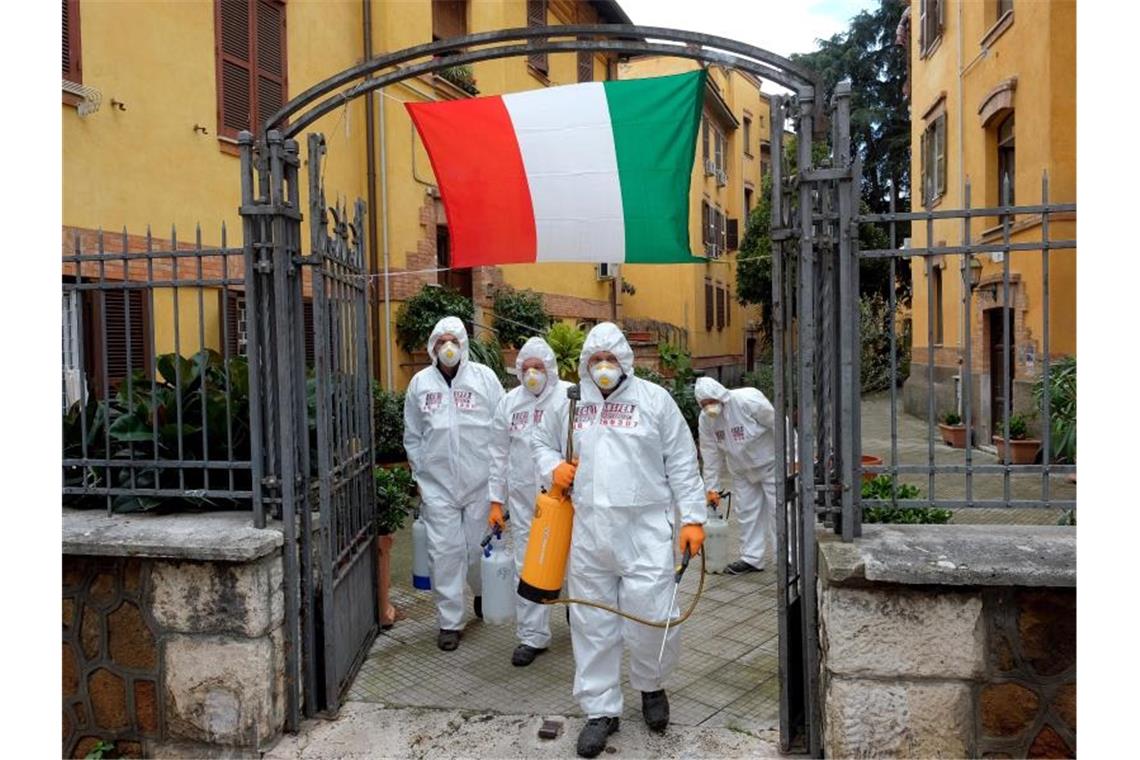 Arbeiter in Schutzkleidung desinfizieren die Gehwege eines Viertels in Rom. Foto: Mauro Scrobogna/LaPresse/dpa