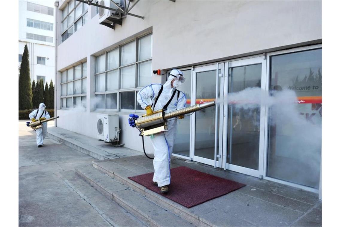 Deutsche aus Coronavirus-Gebiet in Frankfurt angekommen Arbeiter in Schutzkleidung desinfizieren ein Geschäft in der Millionenstadt Qingdao im Osten Chinas. Foto: CHINATOPIX/AP/dpa