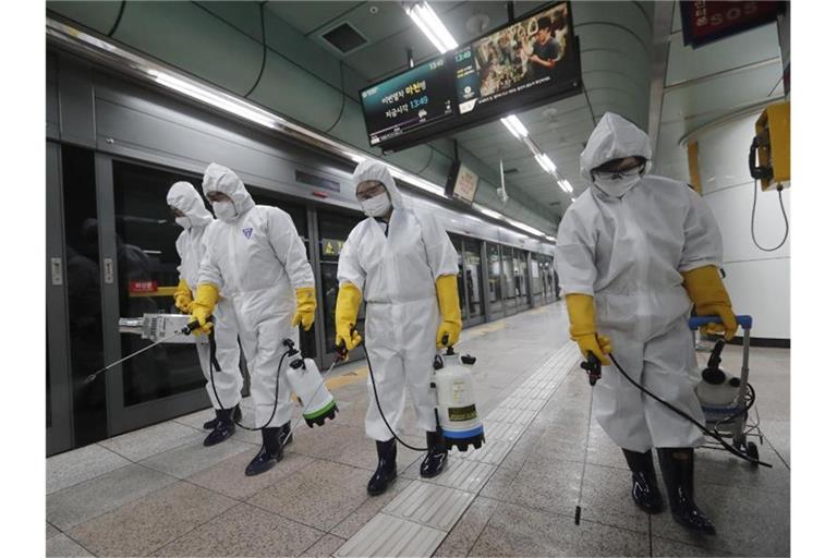 Arbeiter in Schutzkleidung versprühen in einer U-Bahn-Station in Seoul Desinfektionsmittel. Foto: Ahn Young-Joon/AP/dpa