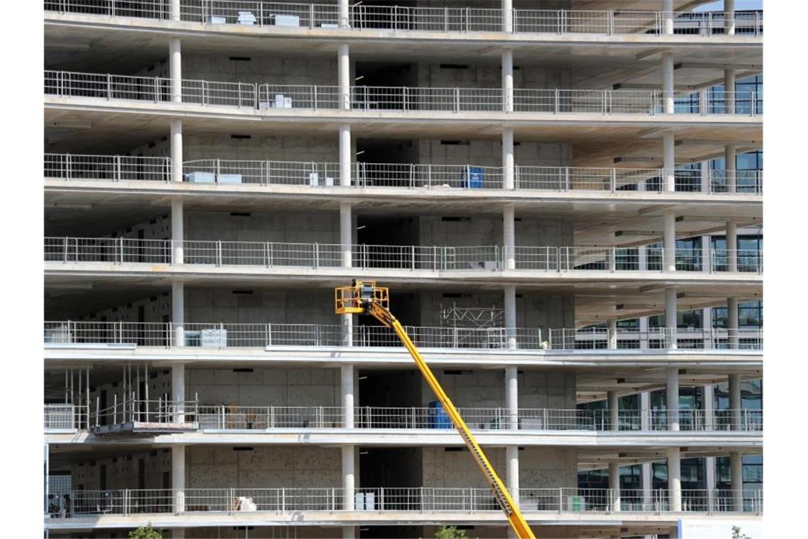 Immobilienfirmen fürchten Corona und fordern Rückendeckung Arbeiter montieren von einer Hebebühne aus Teile an einem Neubau. Foto: Jens Büttner/zb/dpa/Symbolbild
