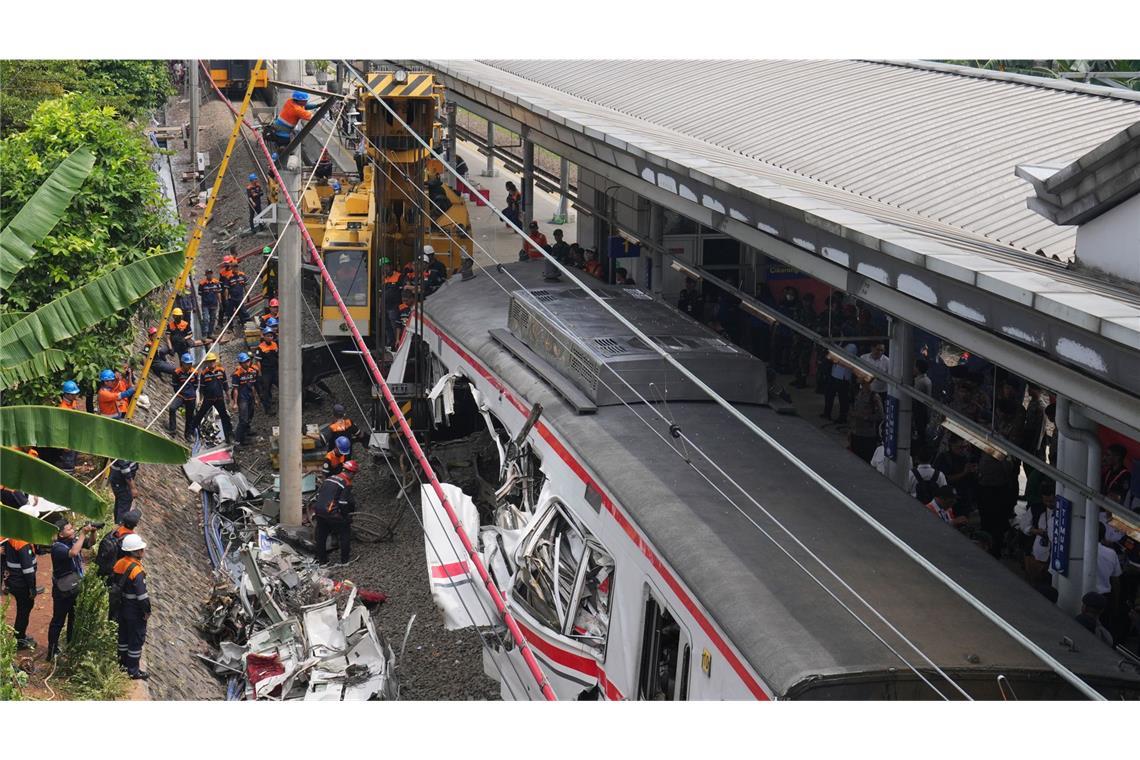 Arbeiter setzen eine schwere Maschine ein, um die Trümmer eines Zuges nach einer Kollision in Bekasi, Indonesien, zu beseitigen.