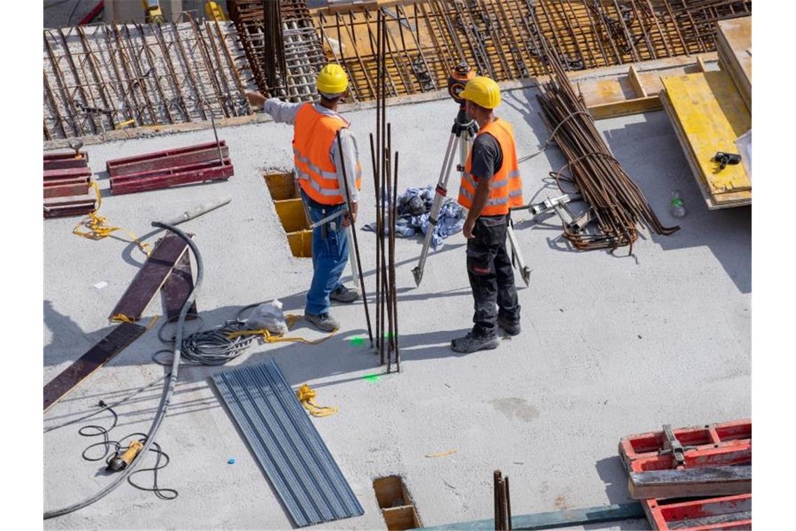 Arbeiter stehen auf einer Baustelle. Foto: Daniel Karmann/Archivbild