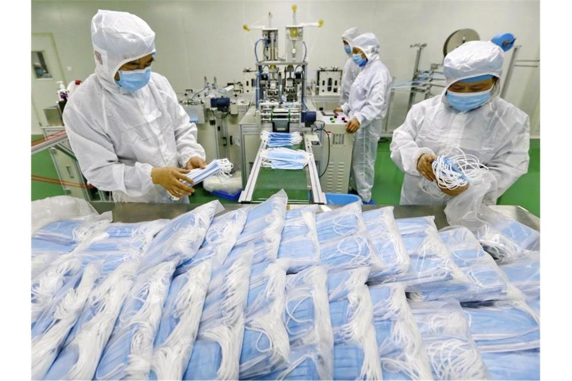Arbeiter verpacken Schutzmasken: Die Zahl neuer Infektionen ist in China erneut gestiegen. Foto: Uncredited/CHINATOPIX/AP/dpa