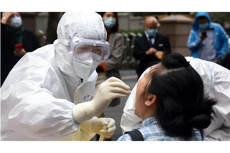 Archivbild aus dem Jahr 2020: Ein Mitarbeiter des Gesundheitswesens im Schutzanzug entnimmt einer Frau in Qingdao eine Abstrichprobe für den COVID-19-Test.