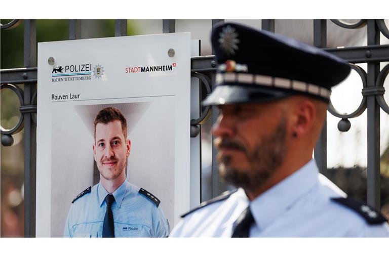 Archivbild: Ein Polizist steht neben einer Gedenktafel für Rouven Laur.