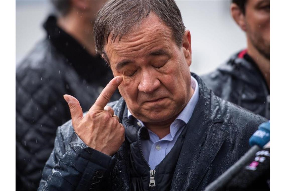 Nach der Flut: Milliarden Euro für den Wiederaufbau Armin Laschet wischt sich den Regen aus dem Auge. Foto: Marius Becker/dpa