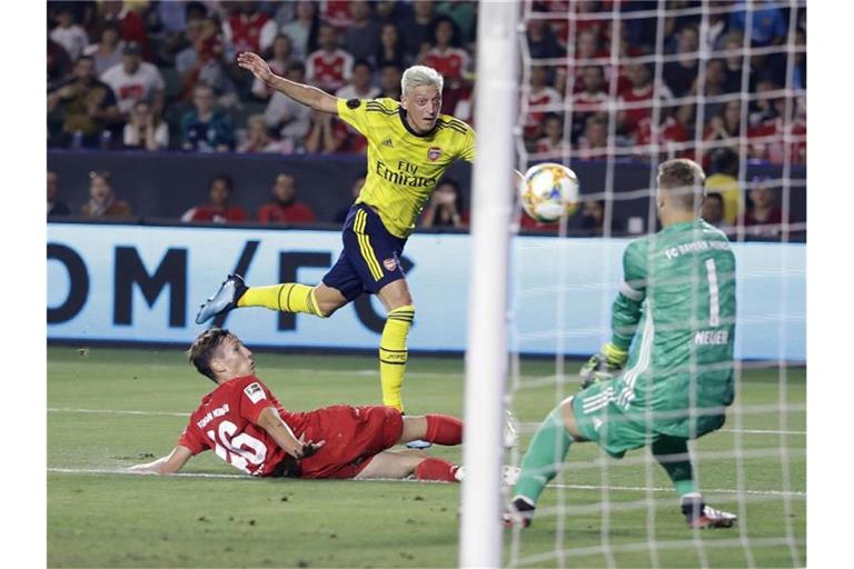 Arsenal-Spieler Mesut Özil (M/oben) kommt gegen Jonas Kehl (l) zum Schuss auf das Tor von Manuel Neuer. Foto: Marcio Jose Sanchez/AP