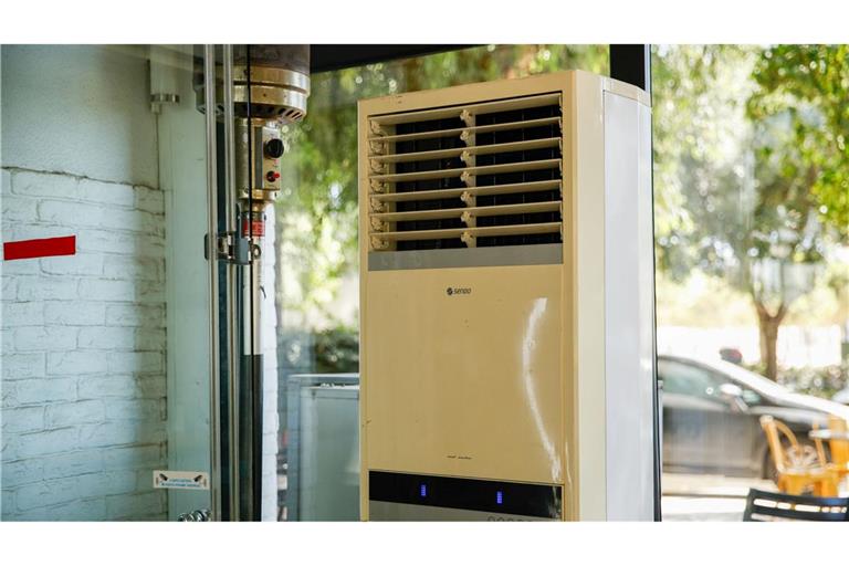 Athen: Eine mobile Klimaanlage steht im verglasten Innenraum eines Cafés. (Archivbild)
