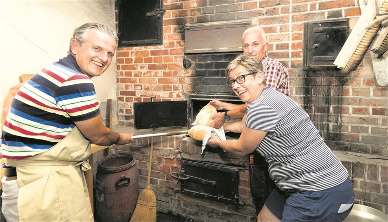 Auch OB Nopper lässt sich in der Kunst des Brotbackens unterweisen. In Elvira Wenzel-Spieth hat er eine gute Lehrerin, Heinz Holzwarth (rechts) weiß zudem viel über die Geschichte der Backhäuser zu erzählen. Foto: J. Fiedler