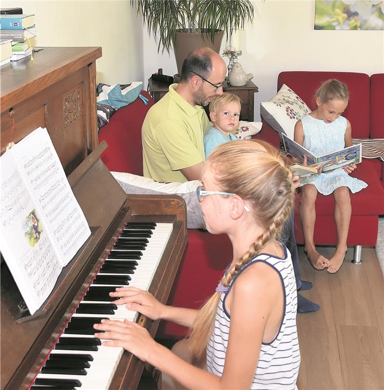 Auch ohne Fernseher wird es bei Familie Vogel selten langweilig: Während die elfjährige Sophia Klavier spielt, liest die siebenjährige Amaris ein Buch. Der zweijährige Jaron lauscht auf dem Schoß von Papa Christian einer Geschichte. Foto: T. Sellmaier