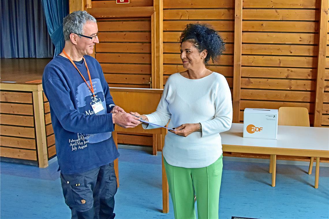 Auch Wahlhelferin Angela Veigel hat sich an der ZDF-Umfrage beteiligt. Alexander Eckstein überreicht ihr die Unterlagen. Foto: Tobias Sellmaier