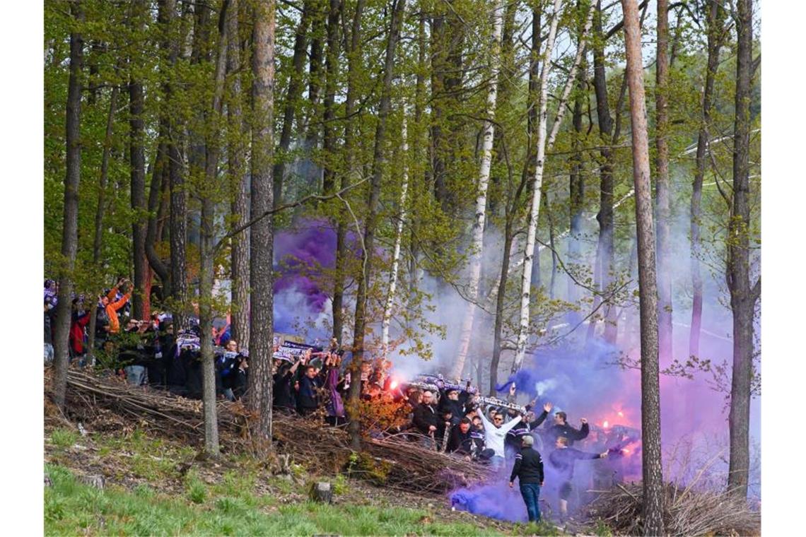 Aues Fans zünden in einem Waldstück neben dem Stadion Bengalos. Foto: Robert Michael/dpa-Zentralbild/dpa