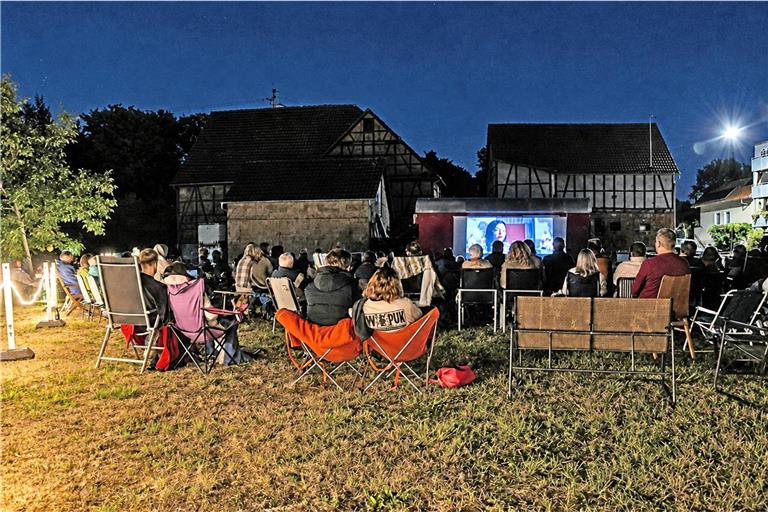 Auf Campingstühlen, Gartenmöbeln und Bierbänken verfolgen an die 100 Gäste den Film auf der Dorfwiese. Foto: Tobias Sellmaier