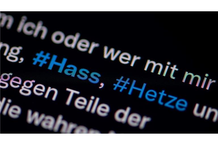 Auf dem Bildschirm eines Smartphones sieht man die Hashtags Hass und Hetze in einem Twitter-Post.