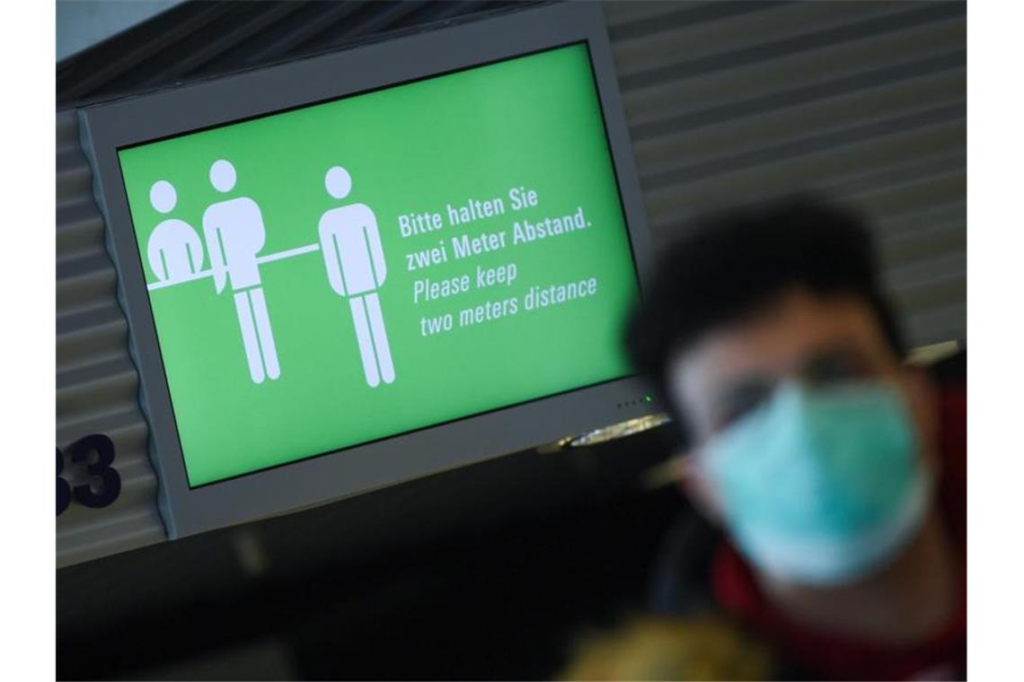 Auf dem Monitor am Frankfurter Flughafen steht: „Bitte halten Sie zwei Meter Abstand!“ Menschen, die nach Deutschland einreisen, müssen bald in eine zweiwöchige Quarantäne. Foto: Arne Dedert/dpa