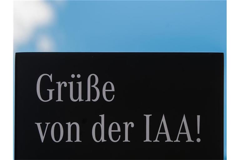 Auf dem Schild eines Ausstellers der Internationalen Automobil-Ausstellung (IAA) steht "Grüße von der IAA". Foto: Andreas Arnold/dpa