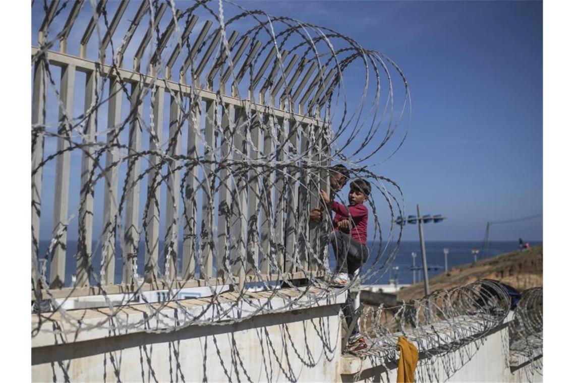 Wie EU-Länder ihre Grenzen gegen Migration befestigen Auf dem Weg zur Grenze zwischen Marokko und Spanien hilft ein Mann einem Jungen über einen Stacheldrahtzaun in der marokkanischen Küstenstadt Fnideq. Foto: Mosa'ab Elshamy/AP/dpa