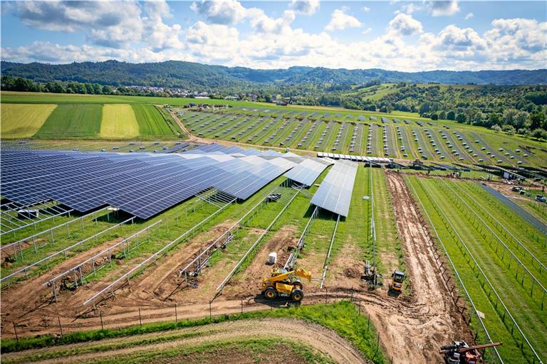 Auf der Baustelle dreht ein kleiner Bagger einsam seine Runden, Bauarbeiter bringen Solarmodule an. Fotos: Alexander Becher