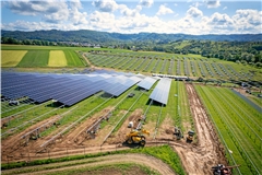 Auf der Baustelle dreht ein kleiner Bagger einsam seine Runden, Bauarbeiter bringen Solarmodule an. Fotos: Alexander Becher