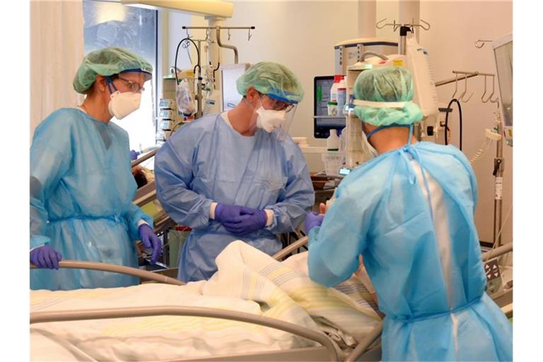Auf der Covid-Station, einem Bereich der Operativen Intensivstation vom Universitätsklinikum Leipzig, stehen Mitarbeiter am Bett eines schwerkranken Patienten. Foto: Waltraud Grubitzsch/dpa-Zentralbild/dpa