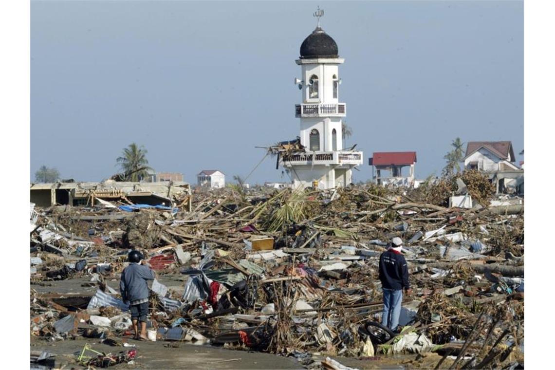 Gebete für Opfer am 15. Jahrestag der Tsunami-Katastrophe Auf der Suche nach Verwertbarem: Zwei Männer in der Trümmerwüste von Banda Aceh in Indonesien. Foto: epa Weda/epa/dpa