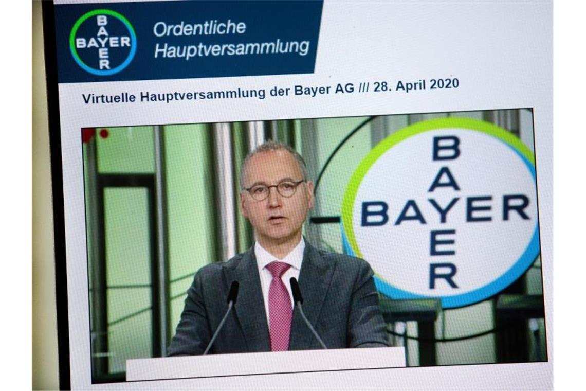 Auf einem Bildschirm ist Bayer Konzernchef Werner Baumann bei seiner Rede zu sehen. Foto: -/Bayer/dpa