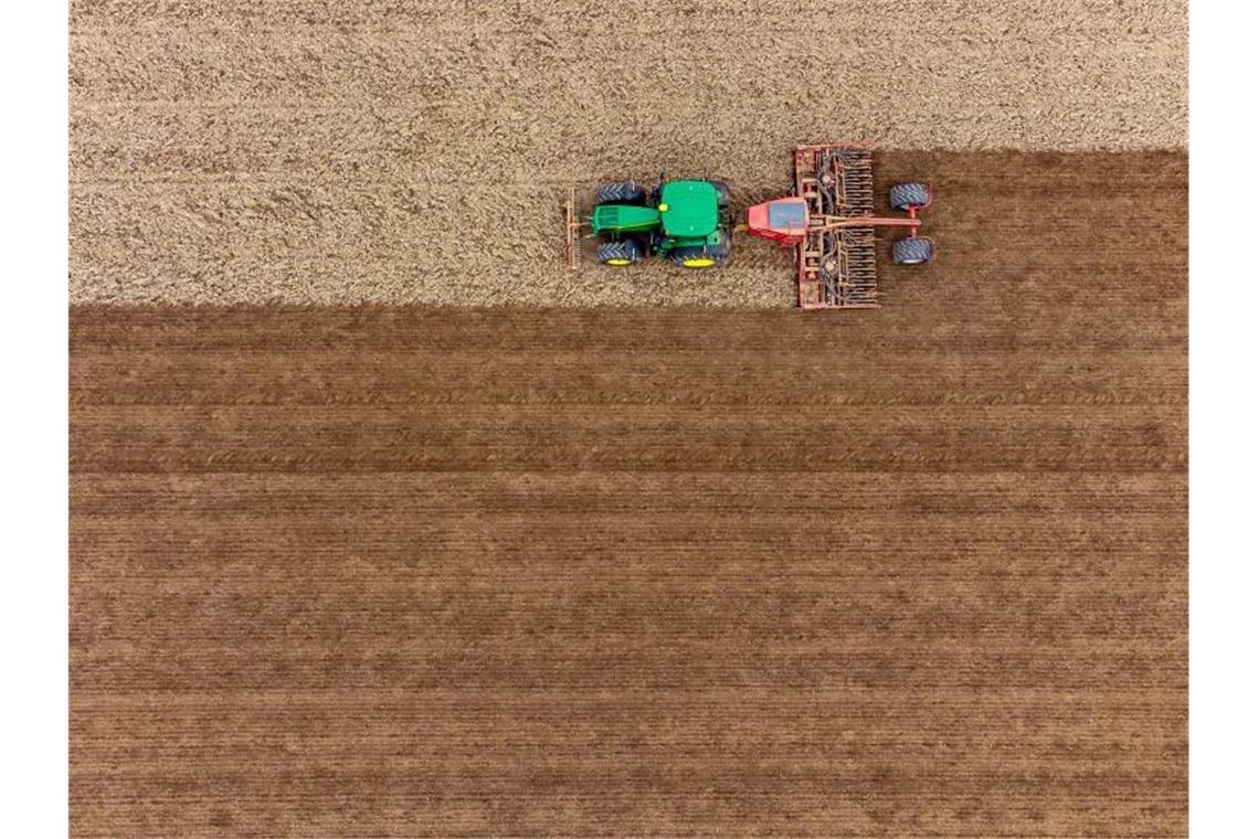 Auf einem Feld wird mit einer Drillmaschine Saatgut von Braugerste angebaut (Luftaufnahme mit Drohne). Foto: Armin Weigel/dpa