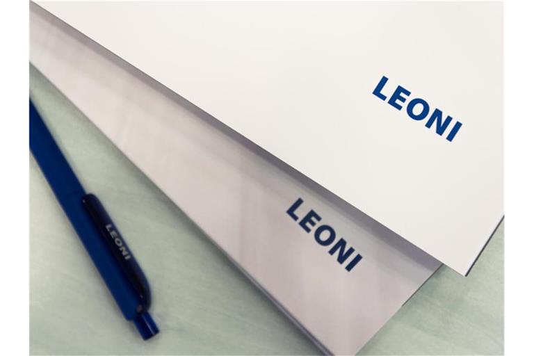 Auf einem Tisch liegen mehrere Blöcke und ein Stift mit der Aufschrift "Leoni". Foto: picture alliance / dpa