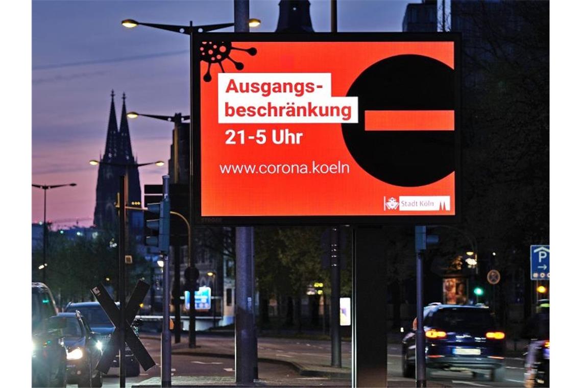 Auf einer Anzeigetafel in Köln wird auf die Ausgangsbeschränkung hingewiesen. Foto: Oliver Berg/dpa