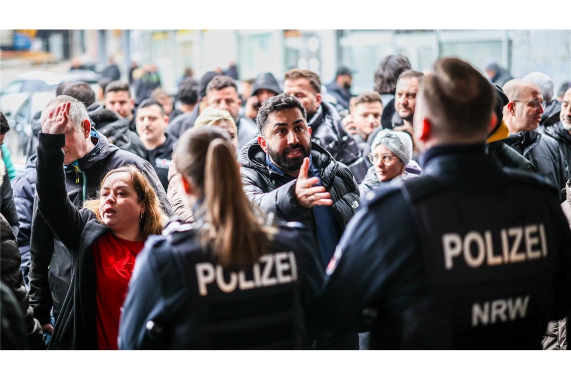 Aufgebrachte Kunden diskutieren vor der Sparkassenfiliale mit Polizeibeamten (Archivfoto)