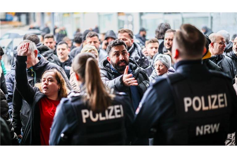 Aufgebrachte Kunden diskutieren vor der Sparkassenfiliale mit Polizeibeamten (Archivfoto)