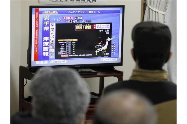 Aufmerksam verfolgen die Menschen die Tsunami-Warnungen für die Gebiete an der japanischen Pazifikküste. Foto: -/kyodo/dpa