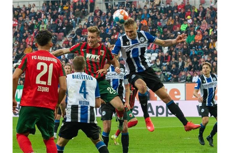 Augsburgs Andre Hahn (hinten, l) und Bielefelds Amos Pieper im Kopfballduell. Foto: Stefan Puchner/dpa